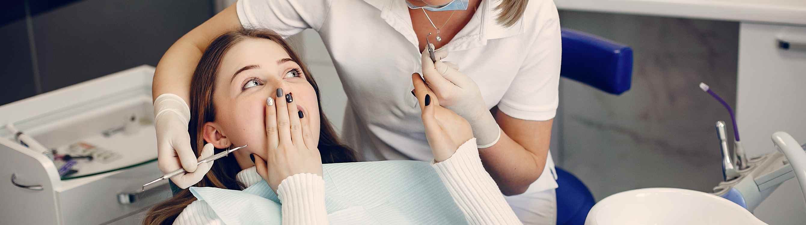 A woman sits in a dentist's chair, her hand gently covering her mouth as she experiences discomfort from an aching tooth. The dentist, wearing a white lab coat and holding dental tools, leans in attentively, ready to alleviate her pain and provide dental care.